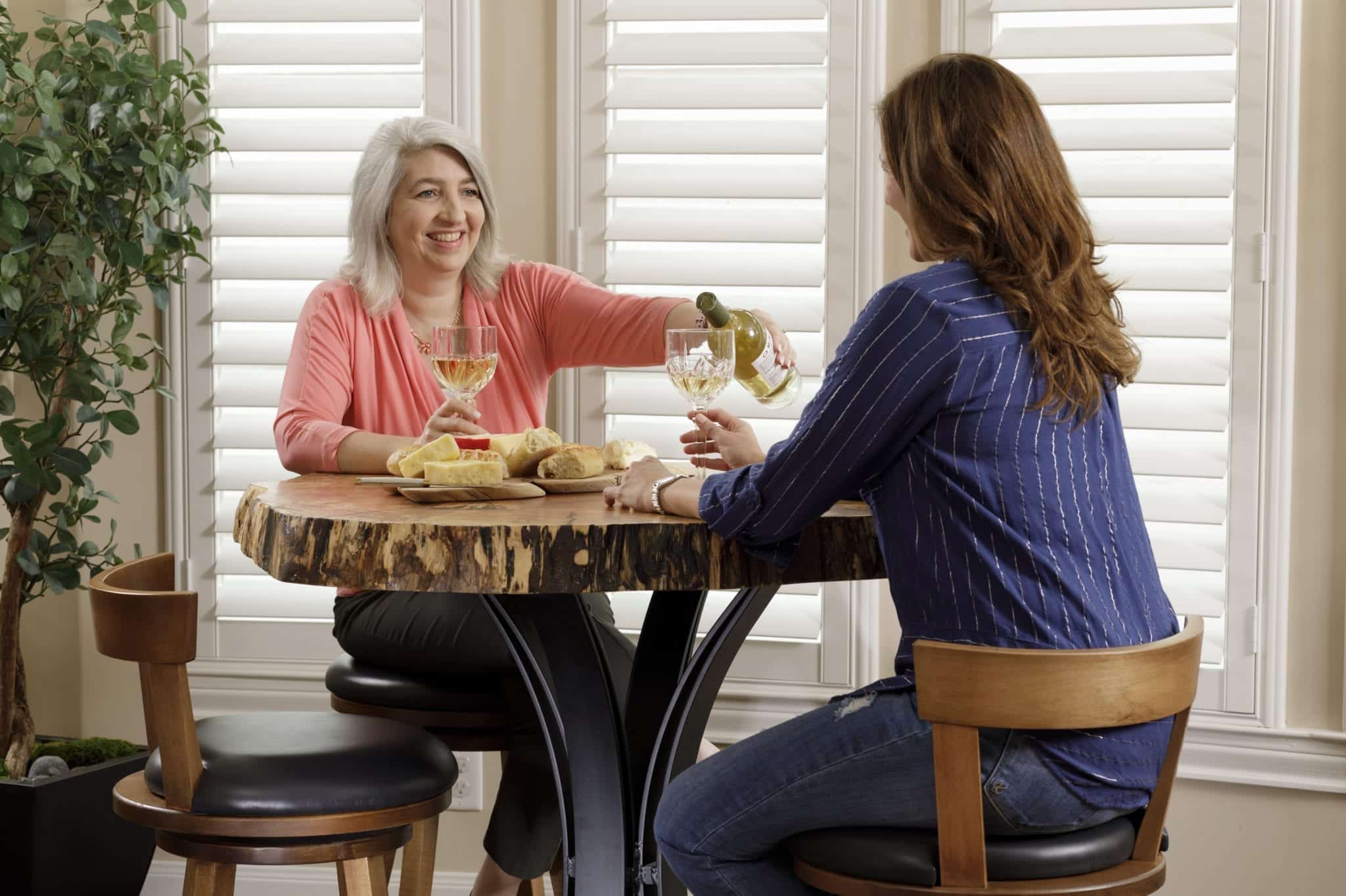 Two women enjoying drinks sitting at a live-edge table.