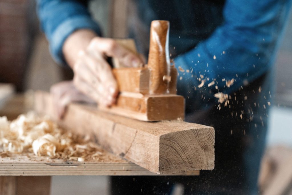 carpenter working with plane on wooden background